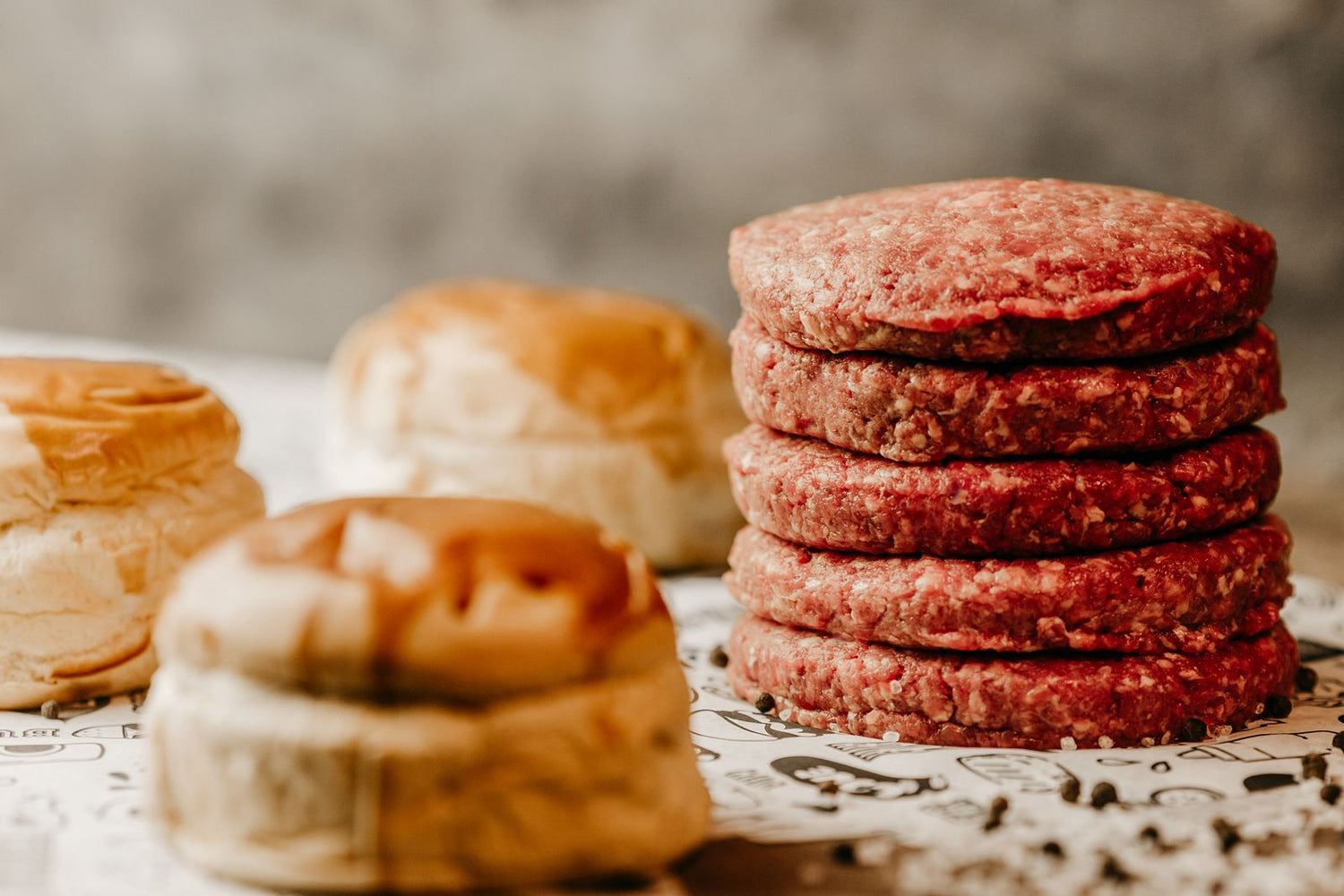 Torre de carne cruda para hamburguesa junto a panes de brioche